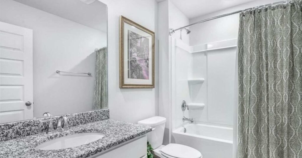 Clean and modern bathroom interior with sink, toilet, and bathtub with shower curtain.